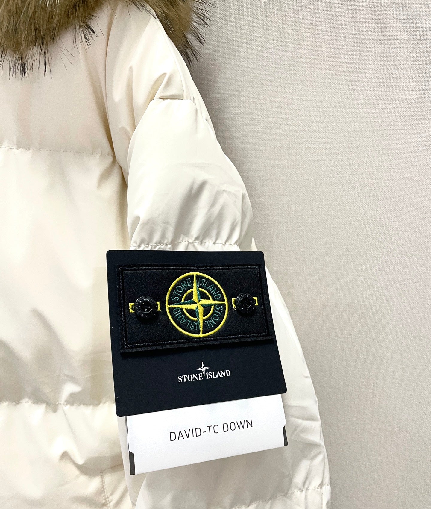 White puffer jacket label with Stone Island patch on sleeve