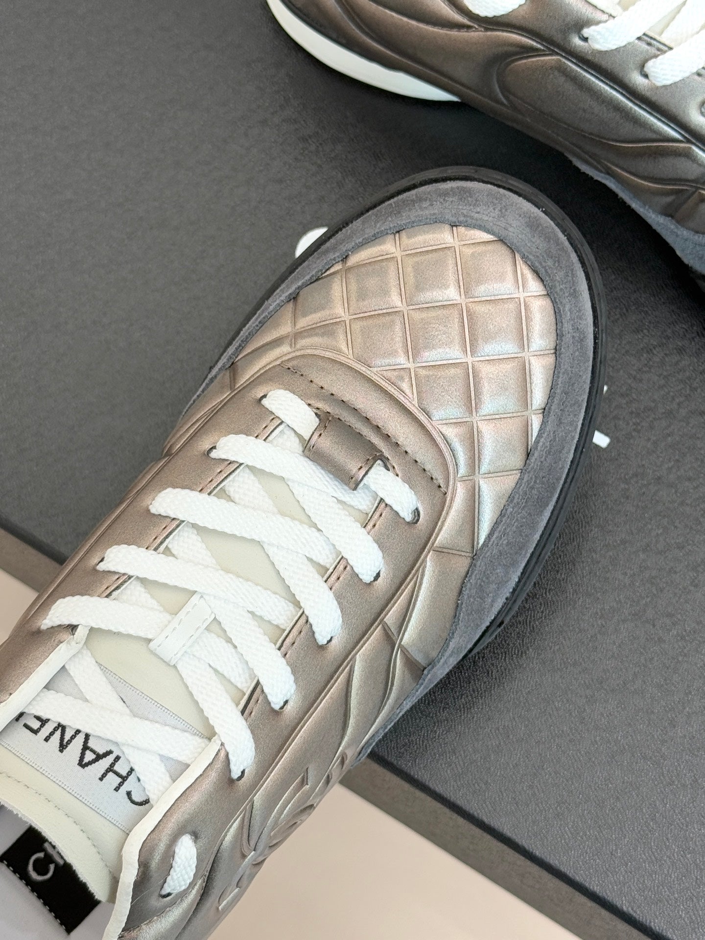 Close-up of metallic beige sneaker toe and laces with textured grid pattern