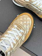 Chanel low-top sneaker close-up: gold quilted leather with white laces