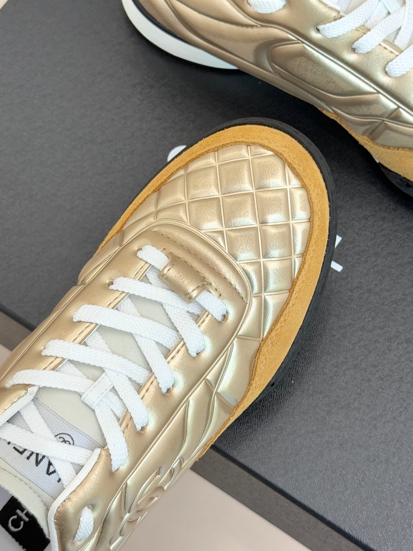 Chanel low-top sneaker close-up: gold quilted leather with white laces