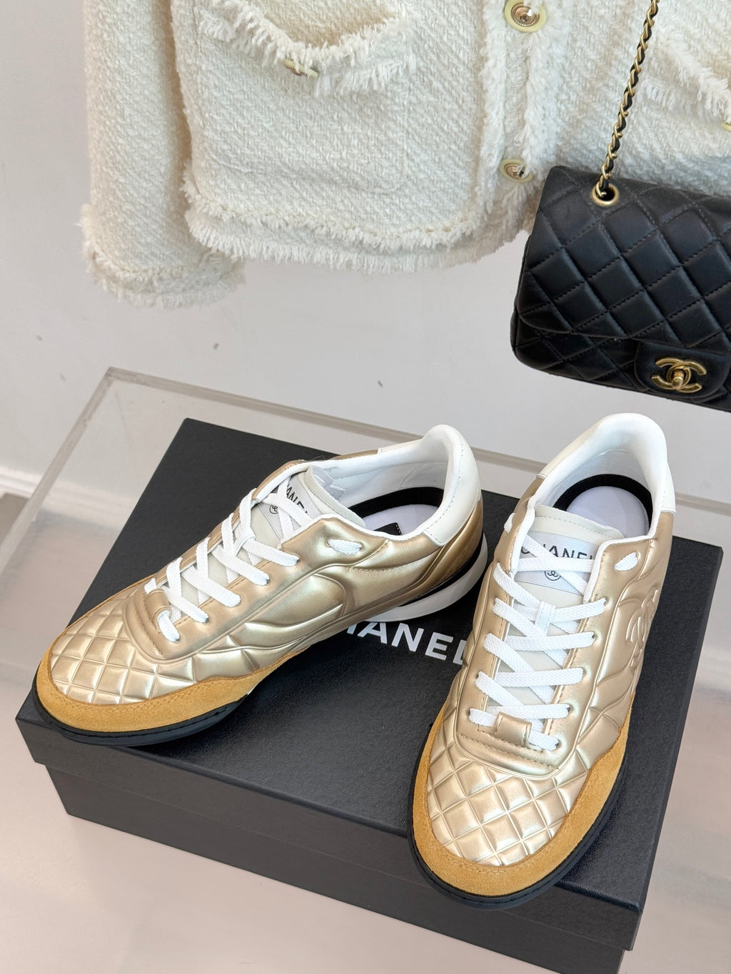 Chanel low-top sneaker pair in gold leather with white lace-up front