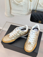 Chanel low-top sneaker pair in gold leather with white lace-up front