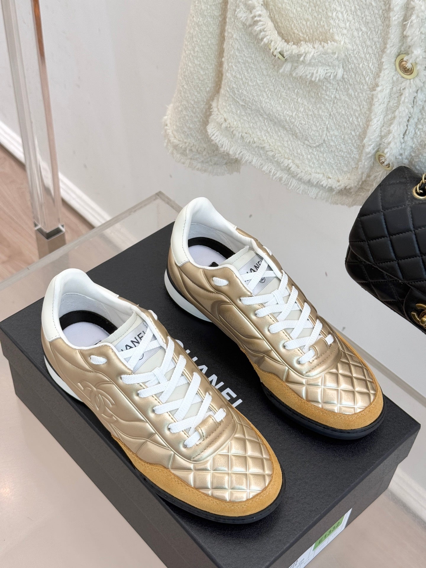 Chanel low-top sneakers on display with gold uppers and white trim