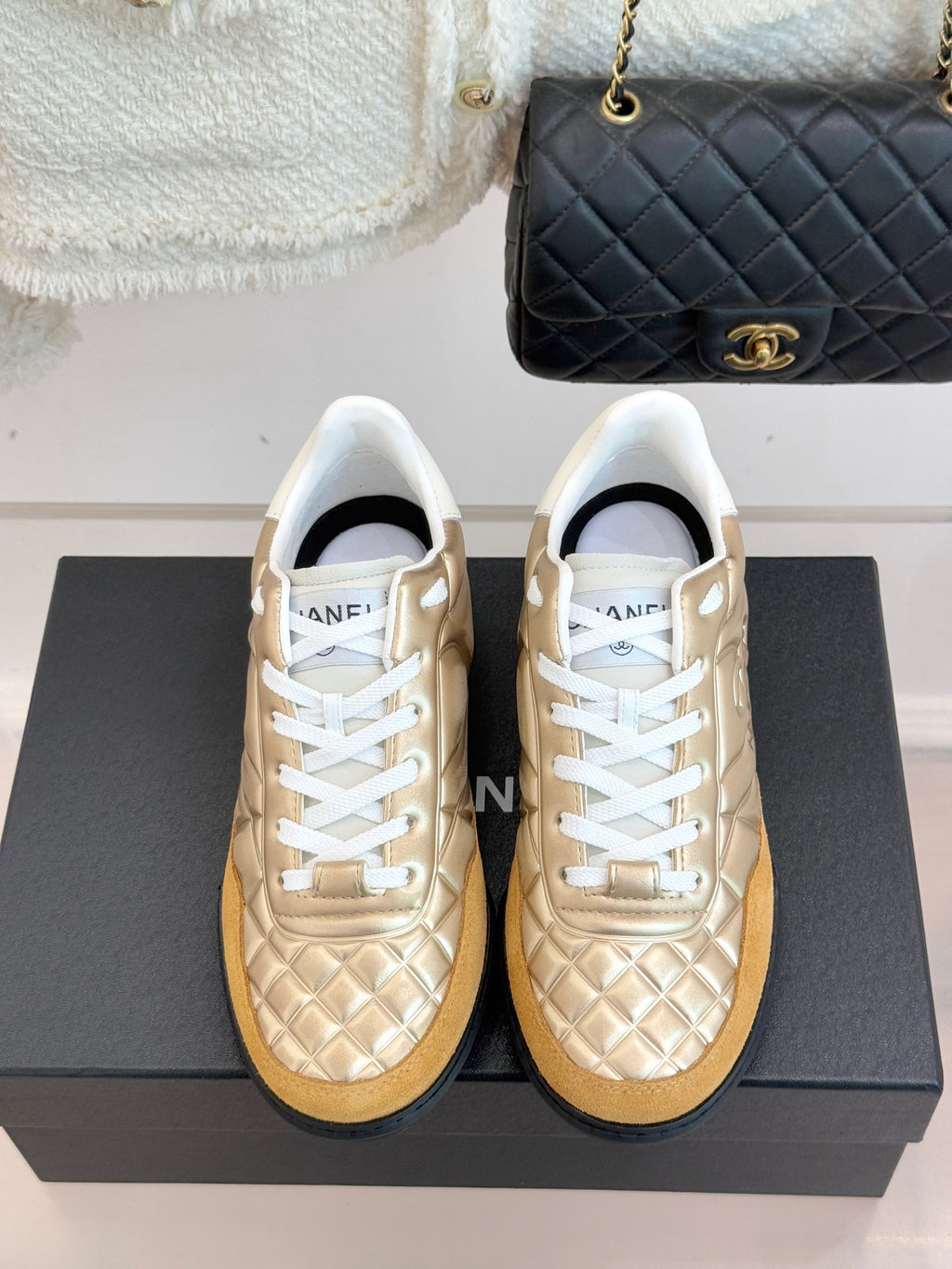 Chanel low-top sneakers with gold quilted uppers, white laces, and gum sole