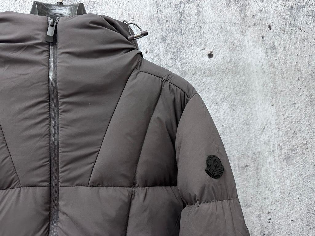 Long padded jacket close-up at zipper and shoulder with patch, dark gray