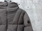 Long padded jacket close-up at zipper and shoulder with patch, dark gray