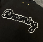 Louis Vuitton long varsity jacket embroidery close-up, white script “Dreaming” on black