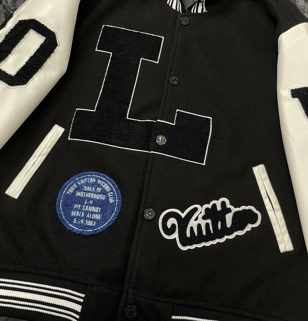 Louis Vuitton long varsity jacket front close-up, black body with white graphic patch and buttons
