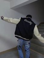 Louis Vuitton long varsity jacket back worn with blue jeans, black body with “Dreaming” script