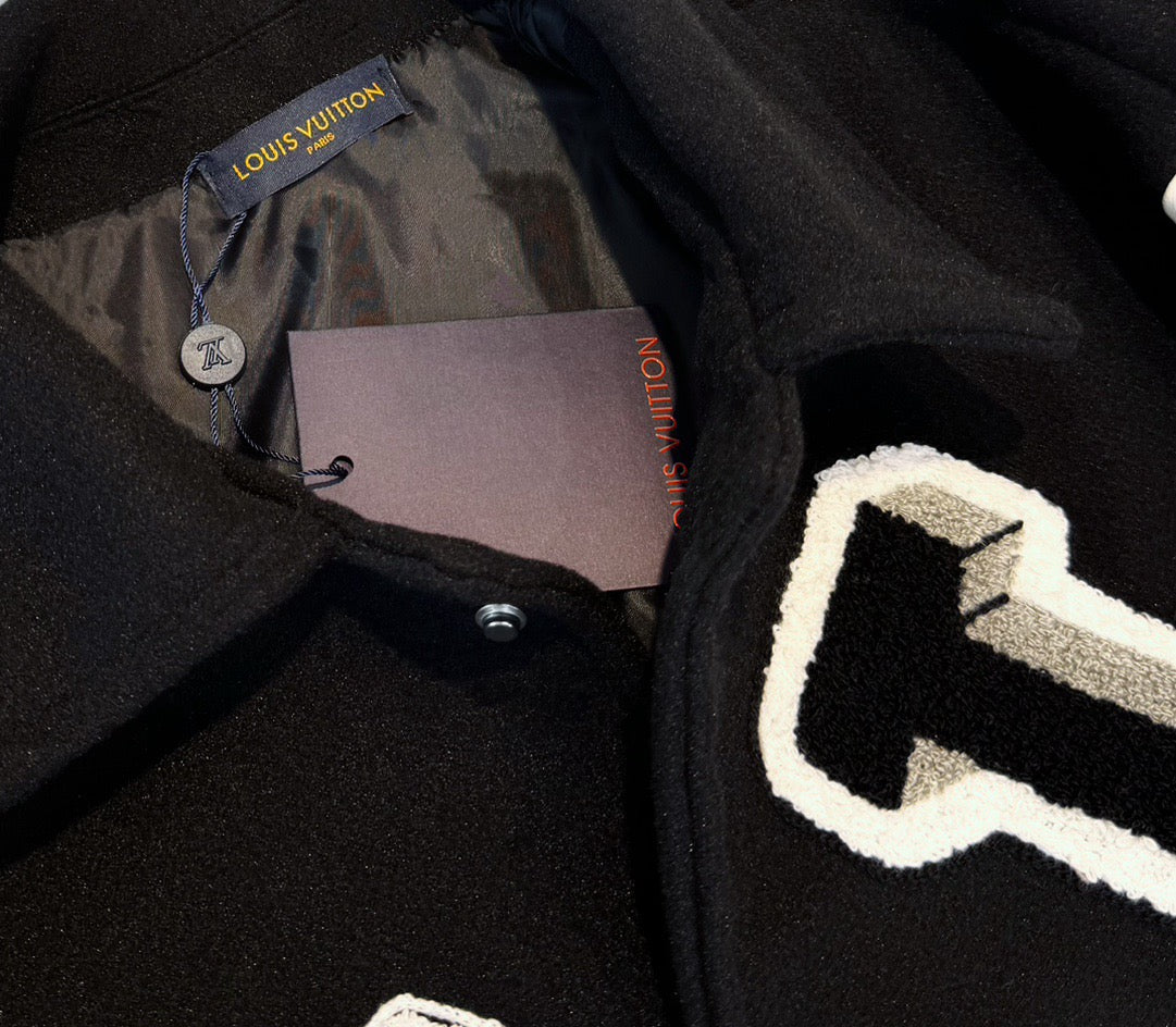 Close-up of black jacket placket with buttons and partial Louis Vuitton logo label