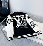 Black and white varsity-style jacket laid out, showing back graphic and striped cuffs