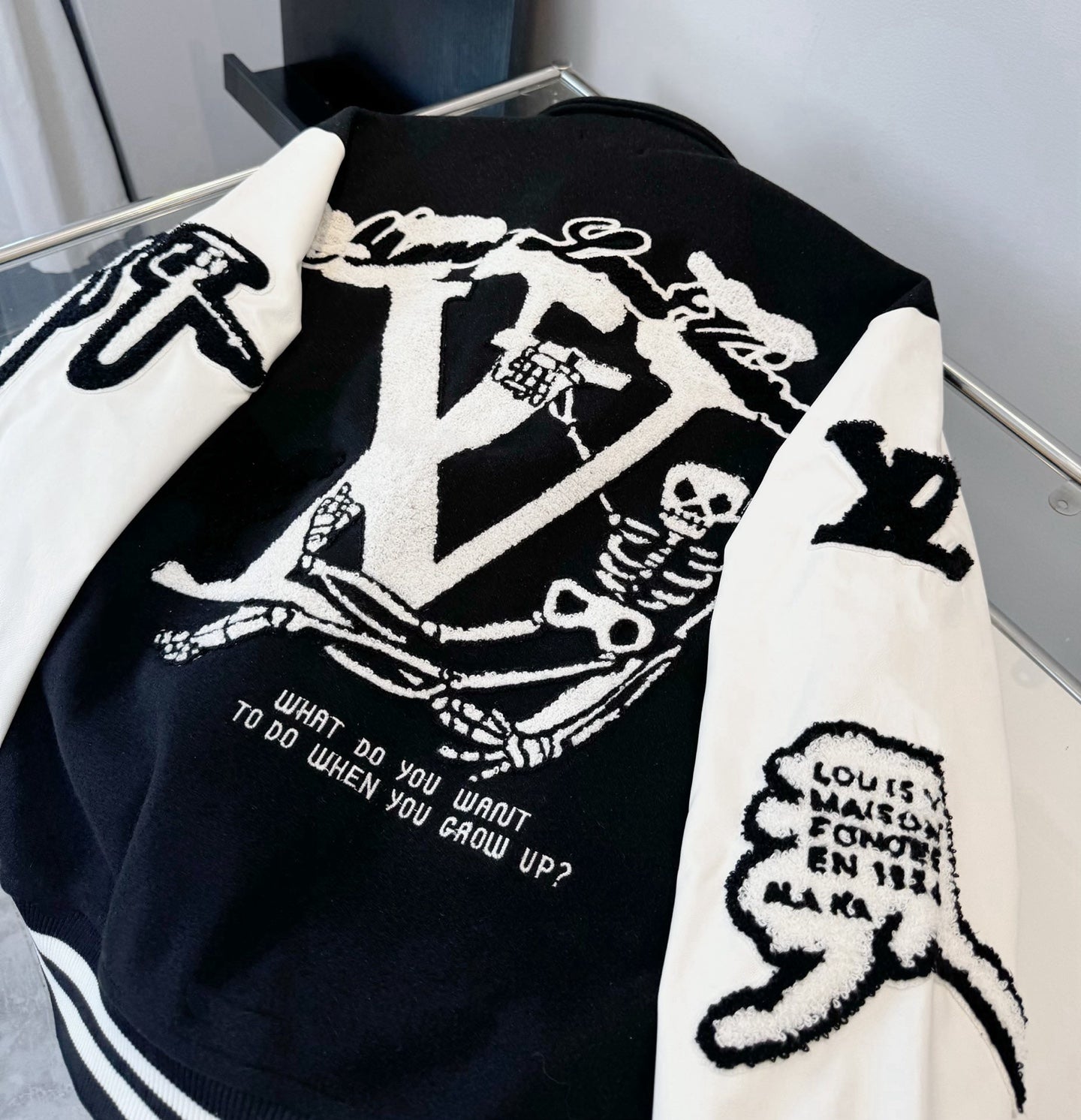 Close-up of black and white varsity-style jacket back graphic with ribbed striped hem