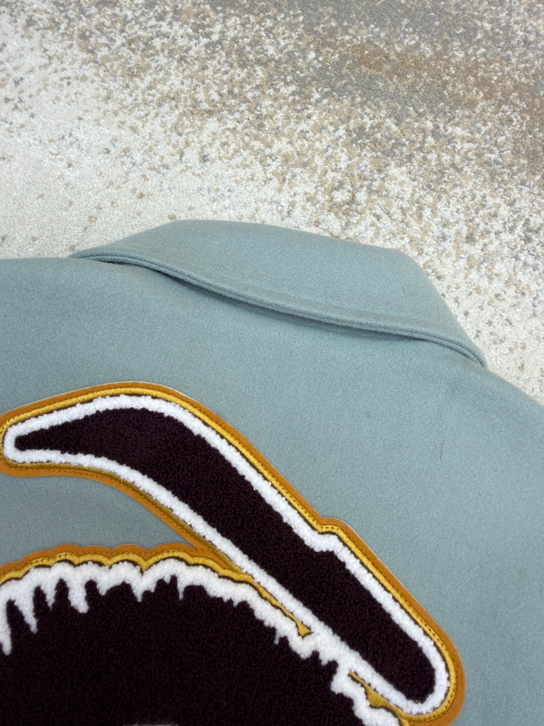Light blue long-sleeve top with black-and-white graphic patch and yellow outline