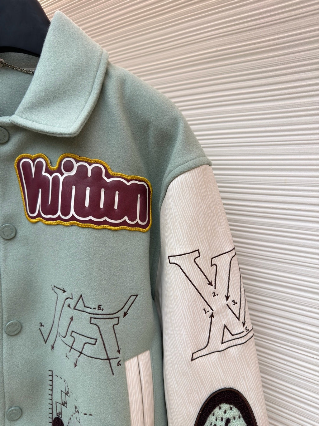 Light blue jacket sleeve, embroidered patch and printed graphic on ribbed cuff