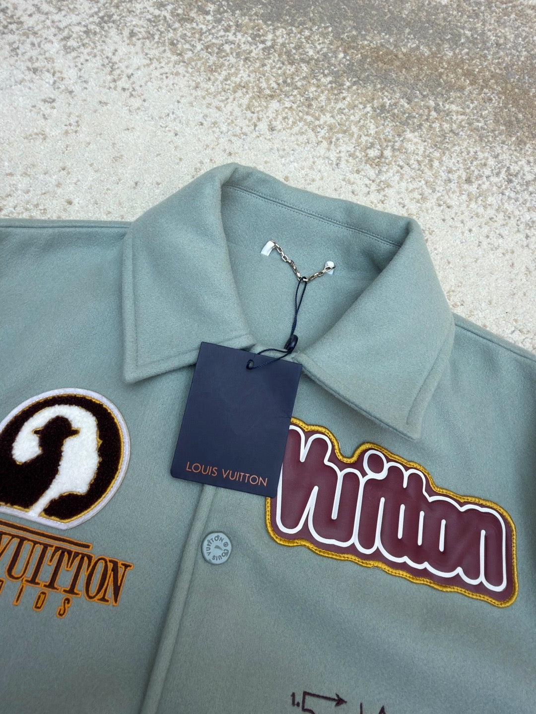 Light blue Louis Vuitton jacket with hang tag, colorful logo patch and snap buttons