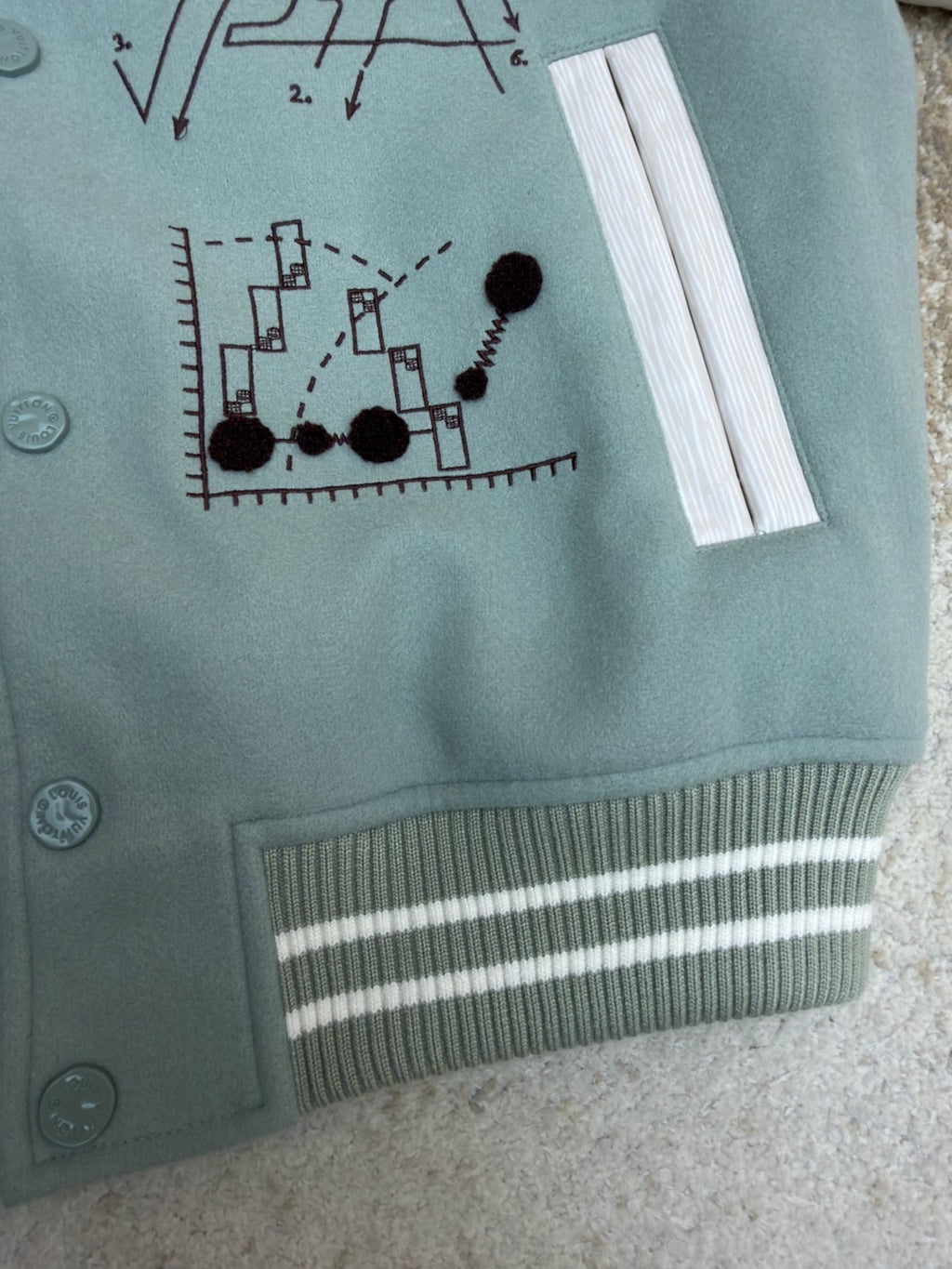 Light blue long-sleeve top with pocket-like flap, graphic print, and striped ribbed hem