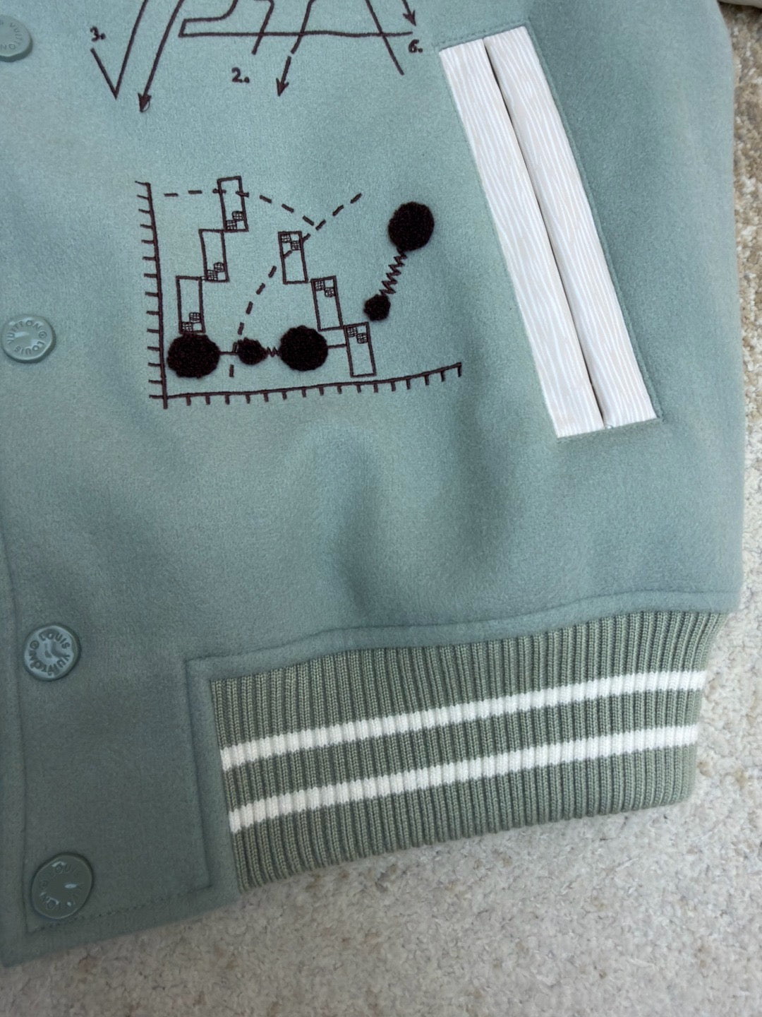 Light blue long-sleeve top with pocket-like flap, graphic print, and striped ribbed hem