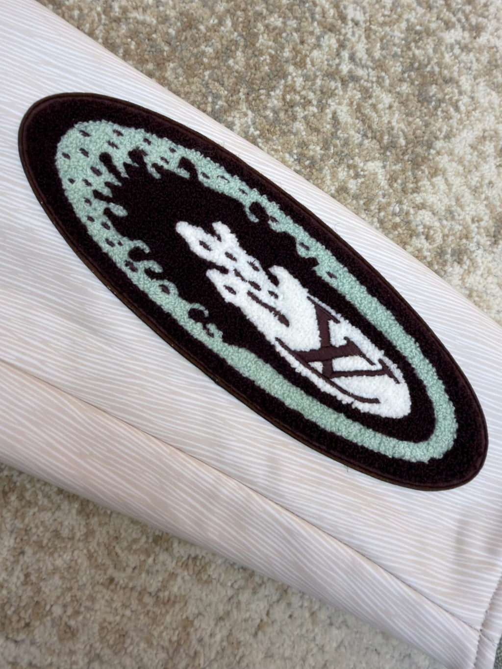 White long-sleeve sleeve with dark oval graphic patch and maroon emblem
