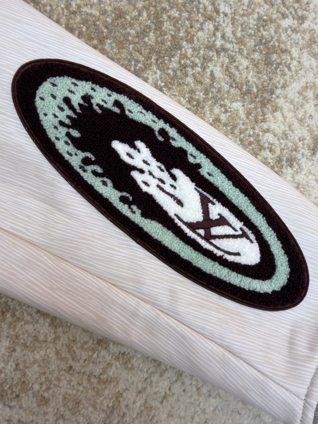White long-sleeve sleeve with dark oval graphic patch and maroon emblem