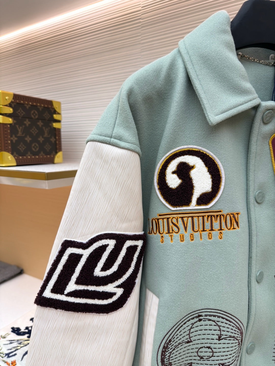 Light blue varsity jacket, front with black-and-white patch and ribbed button placket