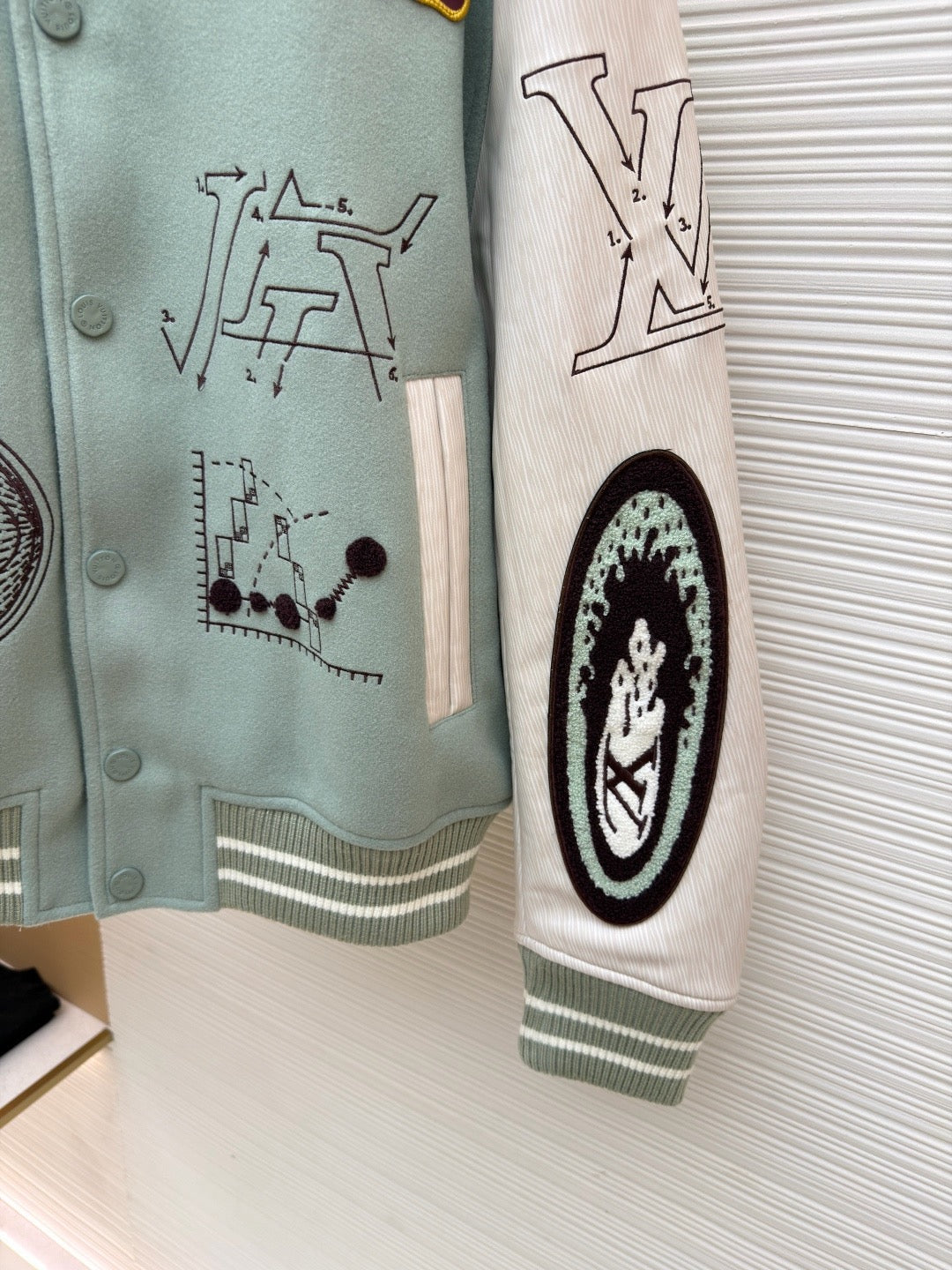 Light blue jacket sleeve close-up, white math-style graphics and ribbed cuff