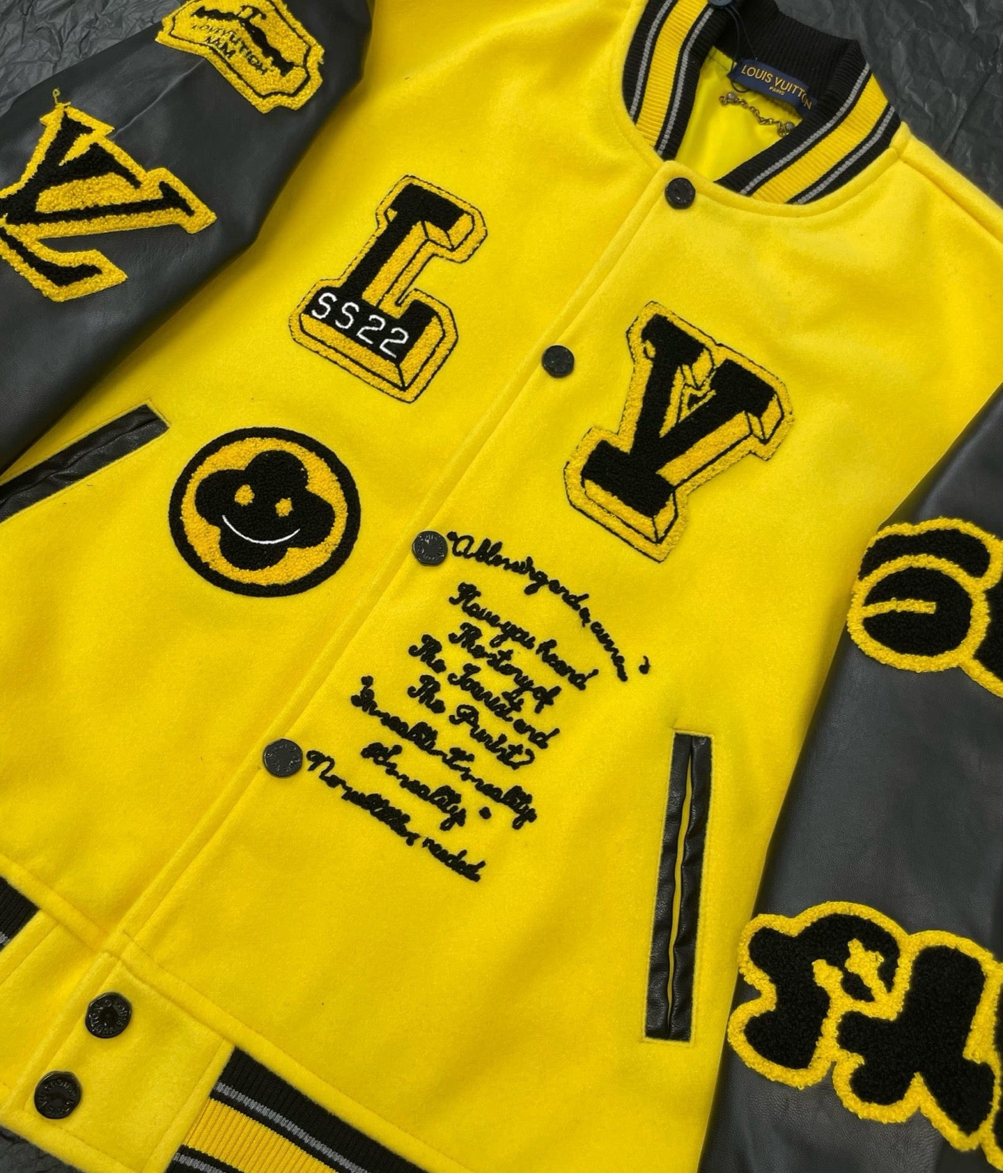 Yellow Louis Vuitton jacket close-up with black graphic icons, snap front, and patch patches