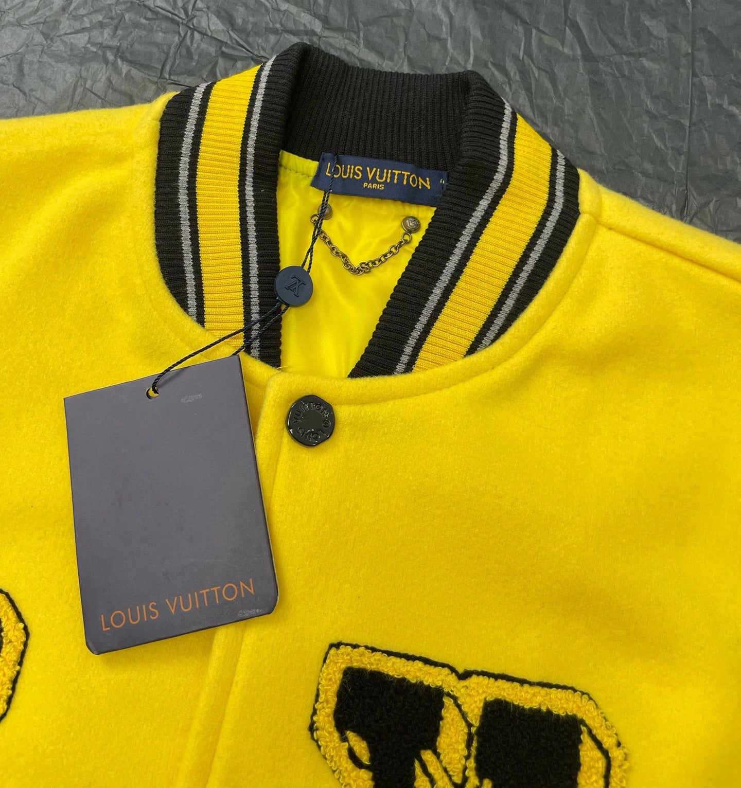 Yellow Louis Vuitton jacket detail with ribbed collar stripes, snap button, hanging tag