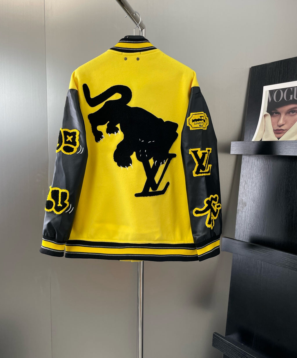 Back view of yellow long Louis Vuitton jacket with black graphic patches and striped cuffs