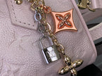 Louis Vuitton light pink bag close-up of charm lock, chain hardware and embossed texture