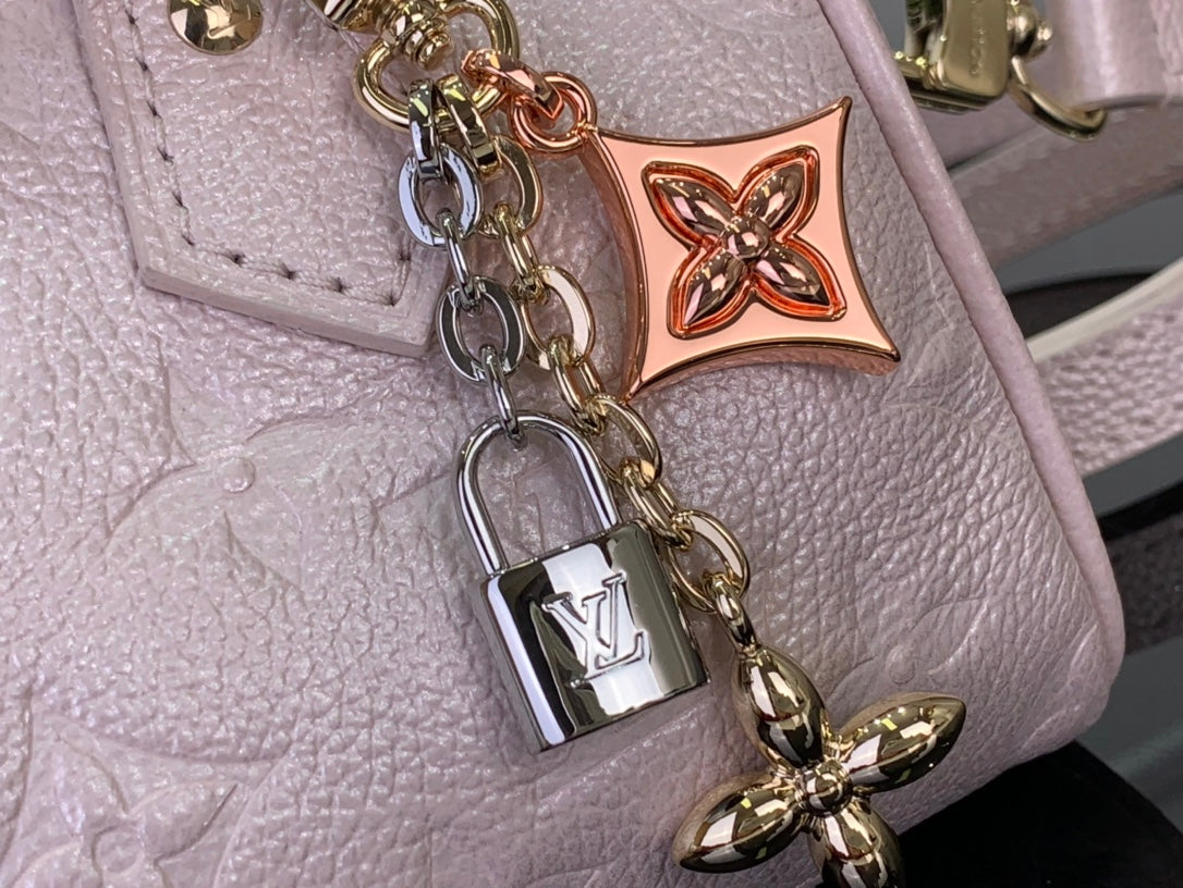 Louis Vuitton light pink bag close-up of charm lock, chain hardware and embossed texture
