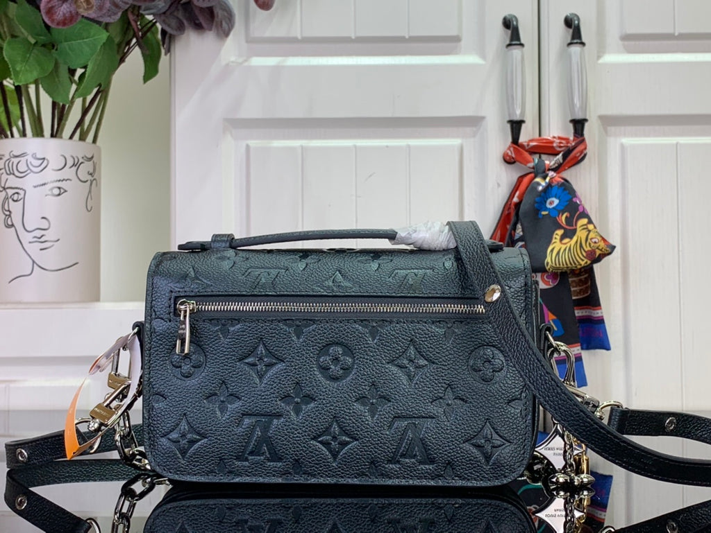 Dark teal monogram handbag with front flap, zipper pocket detail, and chain strap