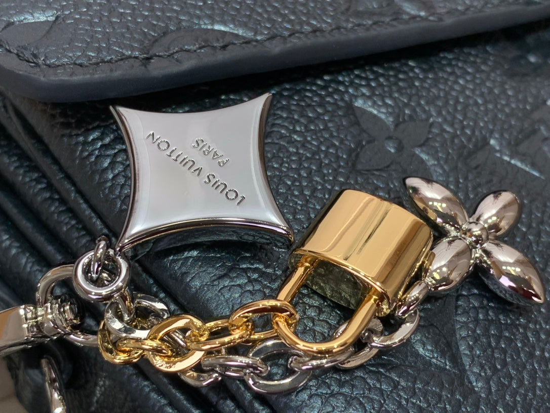 Padlock and bow charms on chain with embossed dark teal leather bag backing