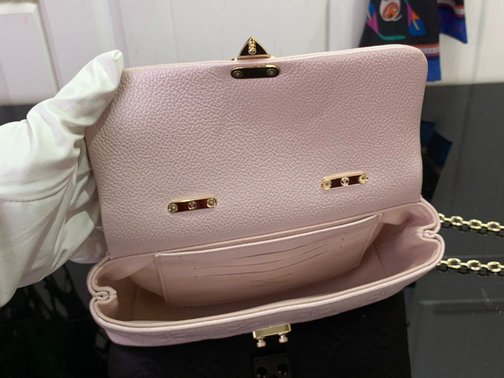 Light pink textured leather handbag with gold clasp studs, top handle, and open interior.
