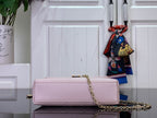 Light pink textured handbag with small gold top clasp and long gold chain strap.