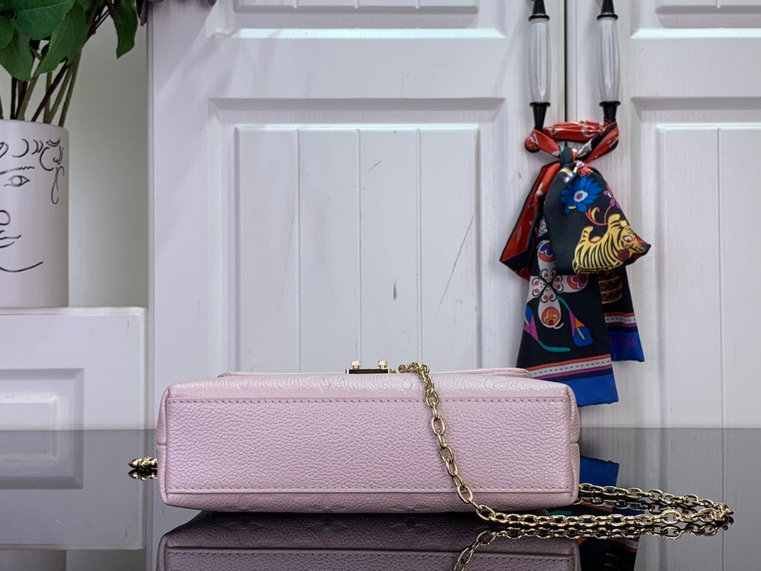 Light pink textured handbag with small gold top clasp and long gold chain strap.