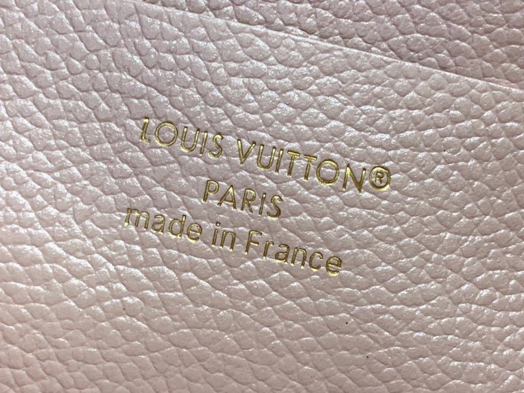 Embossed Louis Vuitton Paris and Made in France on light pink textured leather.