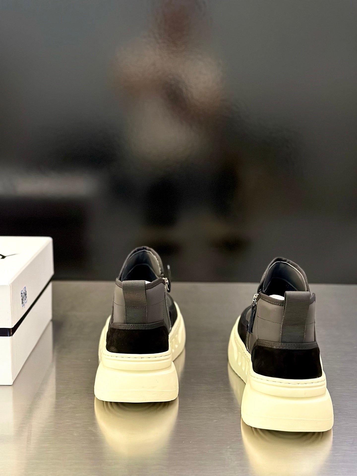 Back view of mid-top slip-on sneakers with dark gray upper and cream sole edges.