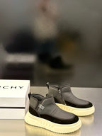 Pair of mid-top slip-on sneakers in dark gray with cream sole and side branding patch.