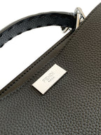 Fendi leather handbag label on pebbled black exterior with stitched edge.