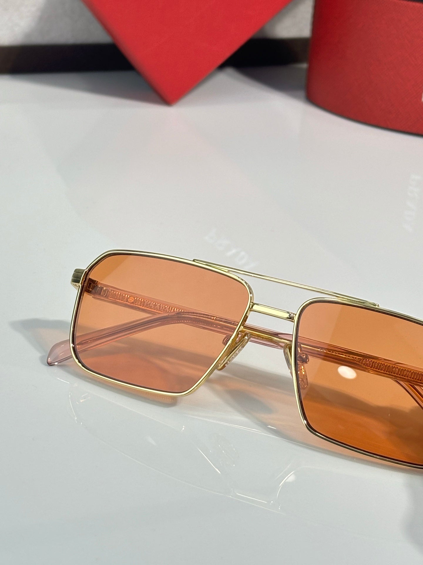 Prada rectangular sunglasses close-up with orange tinted lenses and gold frame