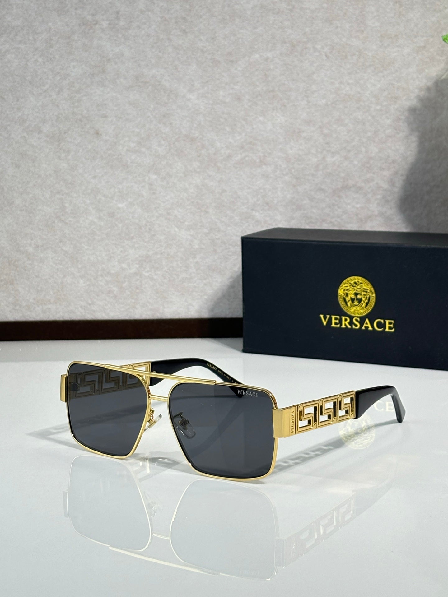 Versace sunglasses with gold-and-black frames and dark gray lenses