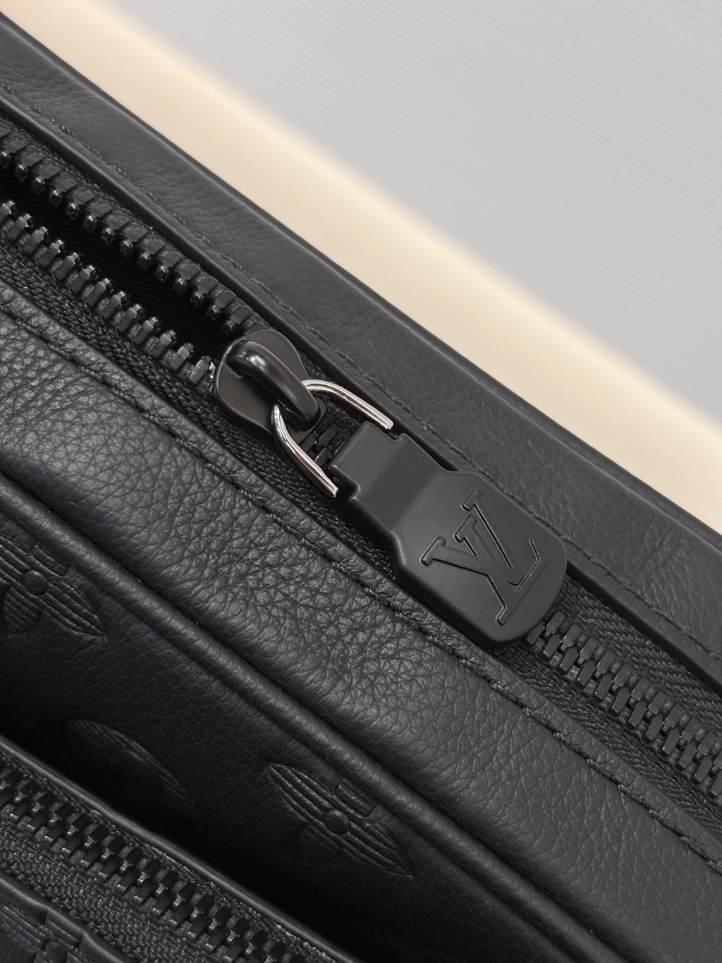 Louis Vuitton black monogram bag close-up of zipper pull and embossed zipper track