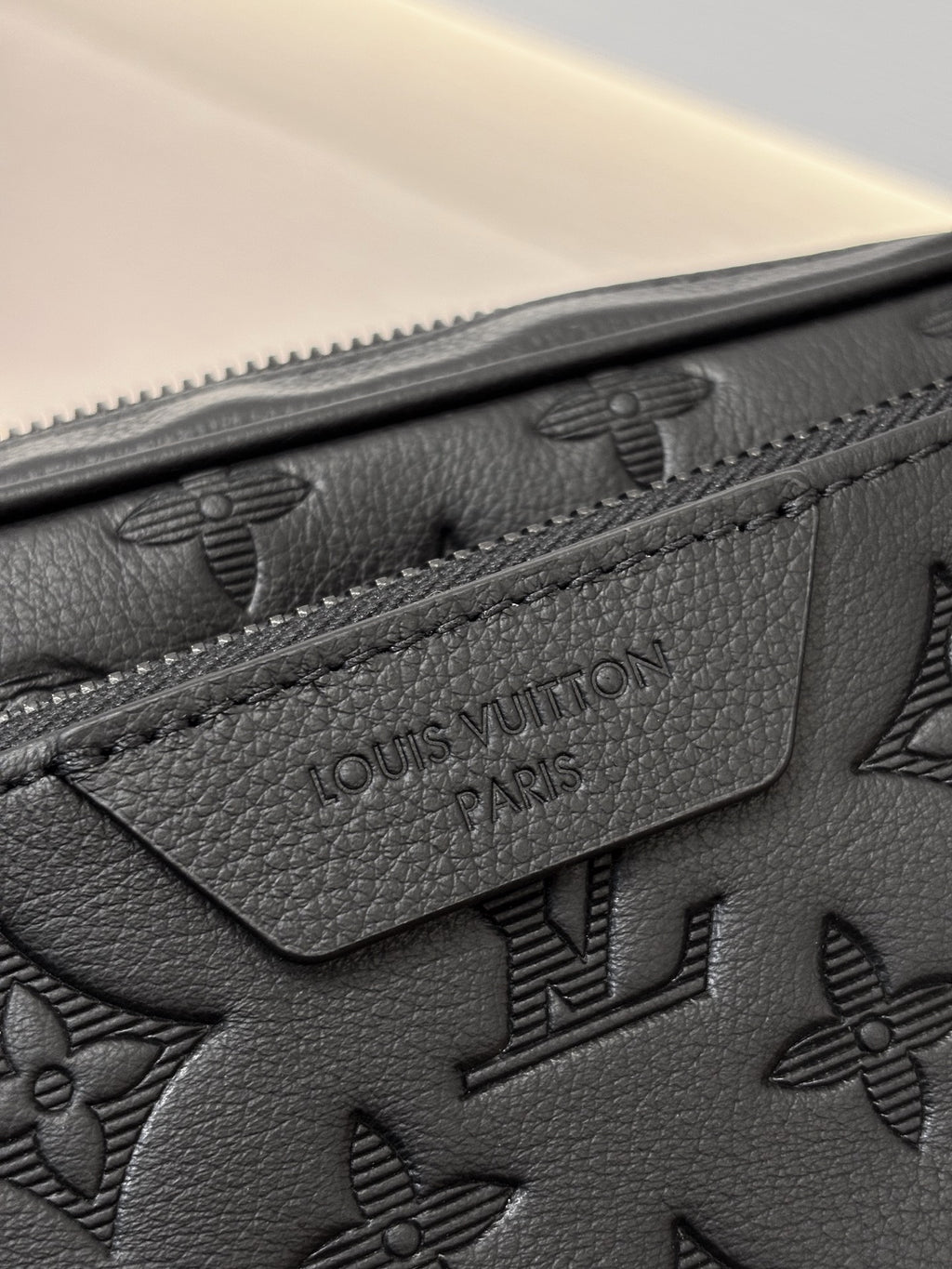 Louis Vuitton black leather bag close-up with embossed monogram and stitched logo patch