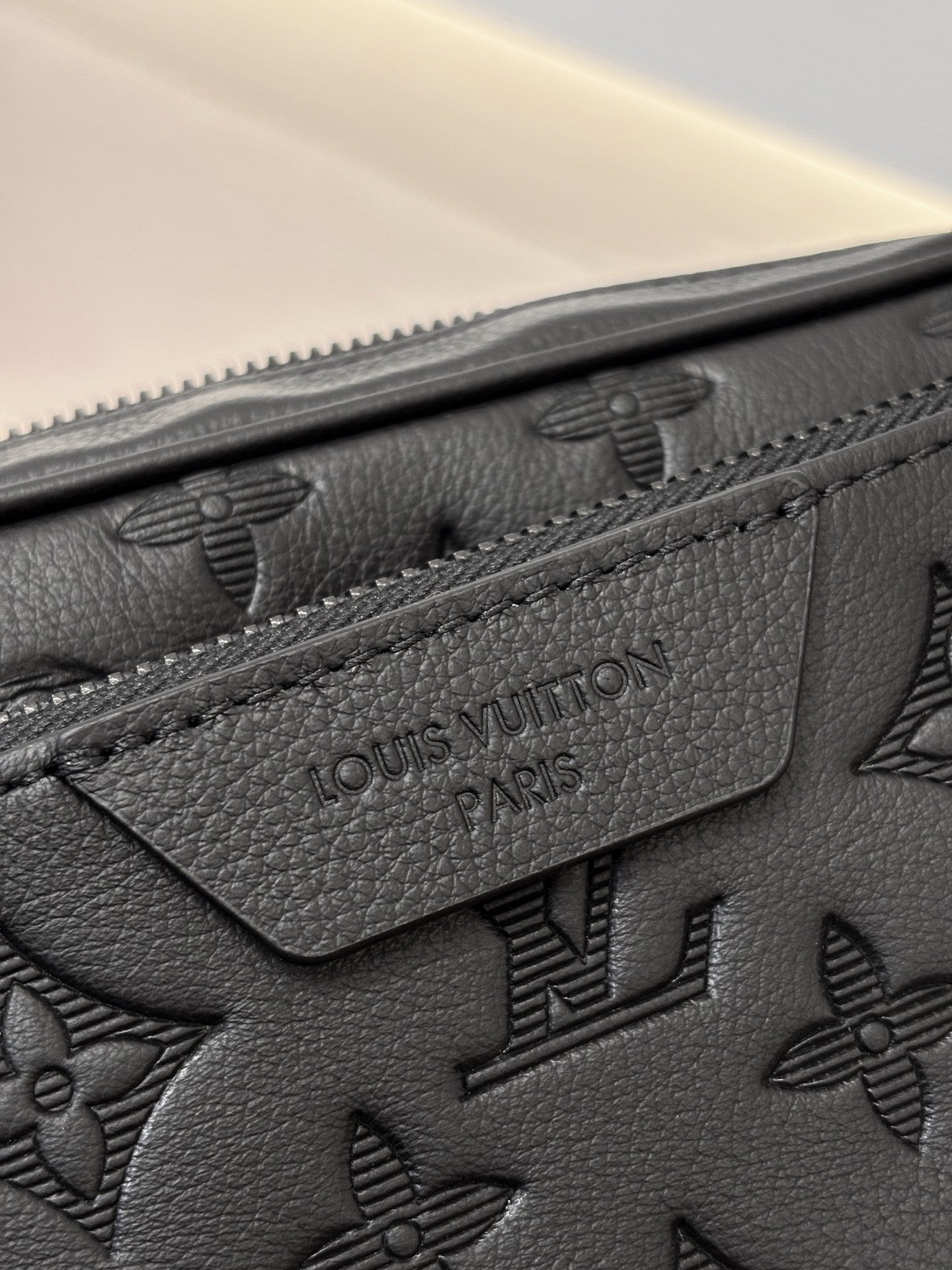 Louis Vuitton black leather bag close-up with embossed monogram and stitched logo patch