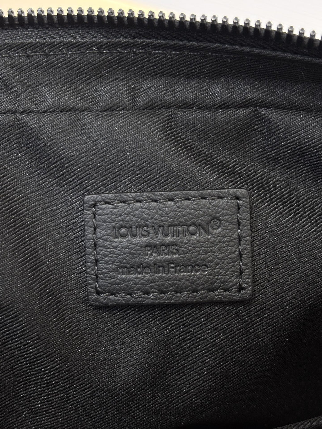 Louis Vuitton black monogram bag close-up of inner label under zipper opening
