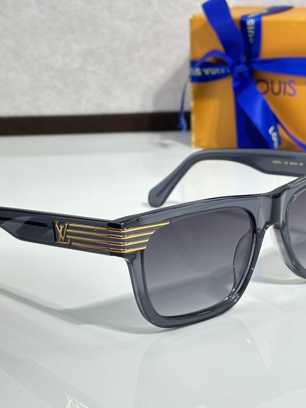 Close-up dark blue eyeglasses with dark tinted lenses and gold LV logo on the temple.