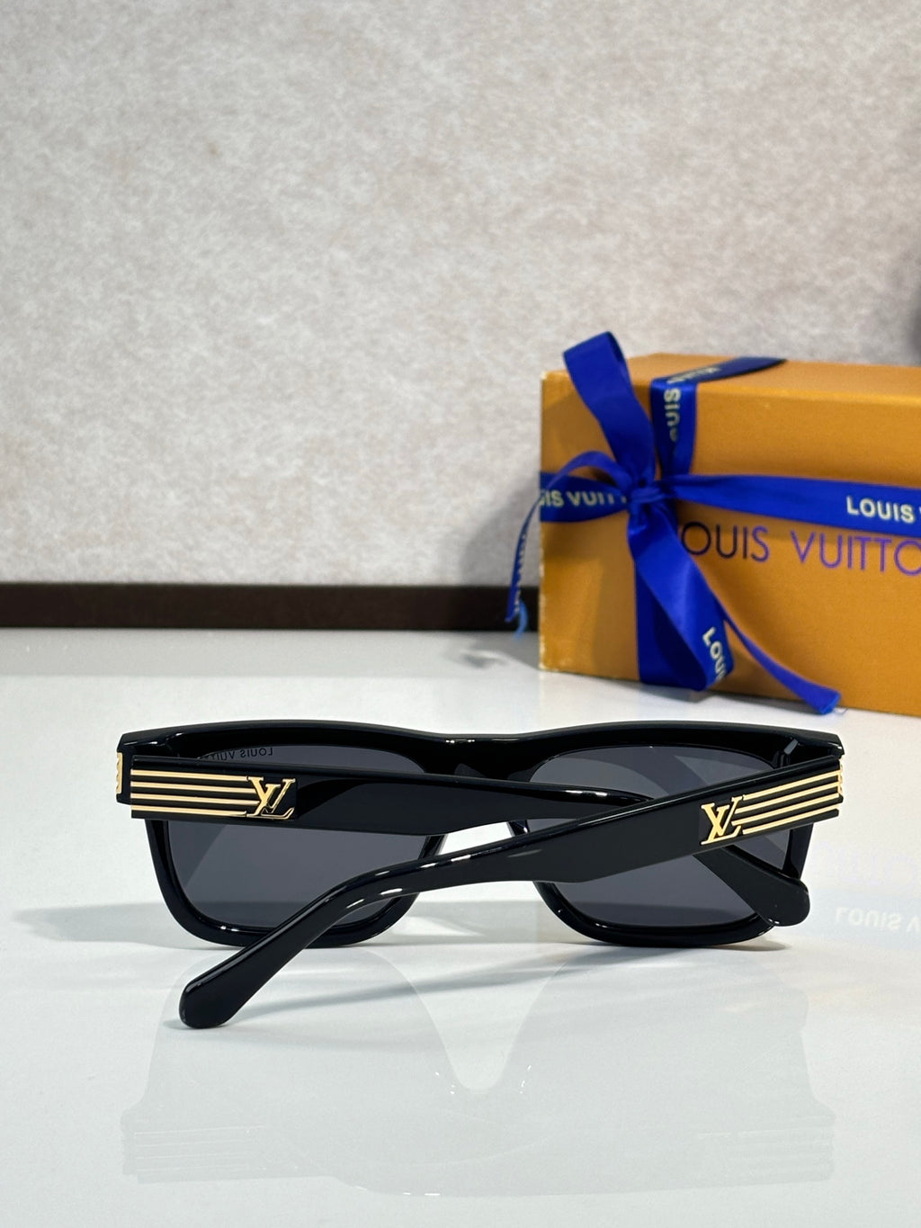 Black geometric eyeglasses with dark tinted lenses and LV logo striped temple detail.