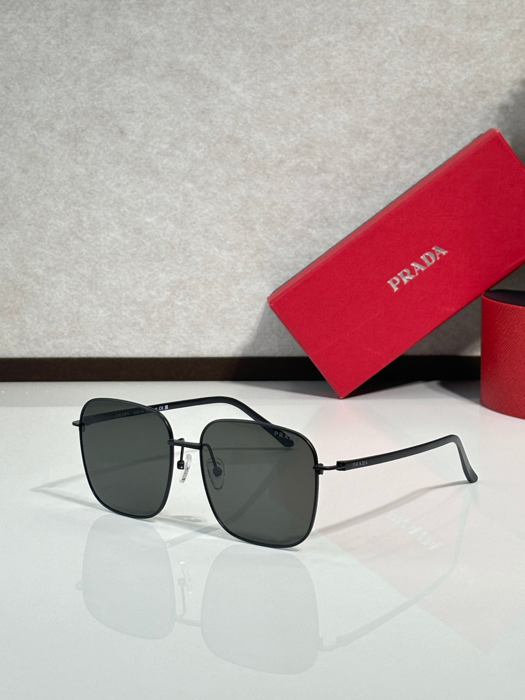Prada sunglasses with black frame and dark gradient lenses, round-rectangular aviator style