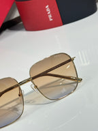 Prada sunglasses close-up with gold frame and amber-tinted lenses, bridge and temple detail