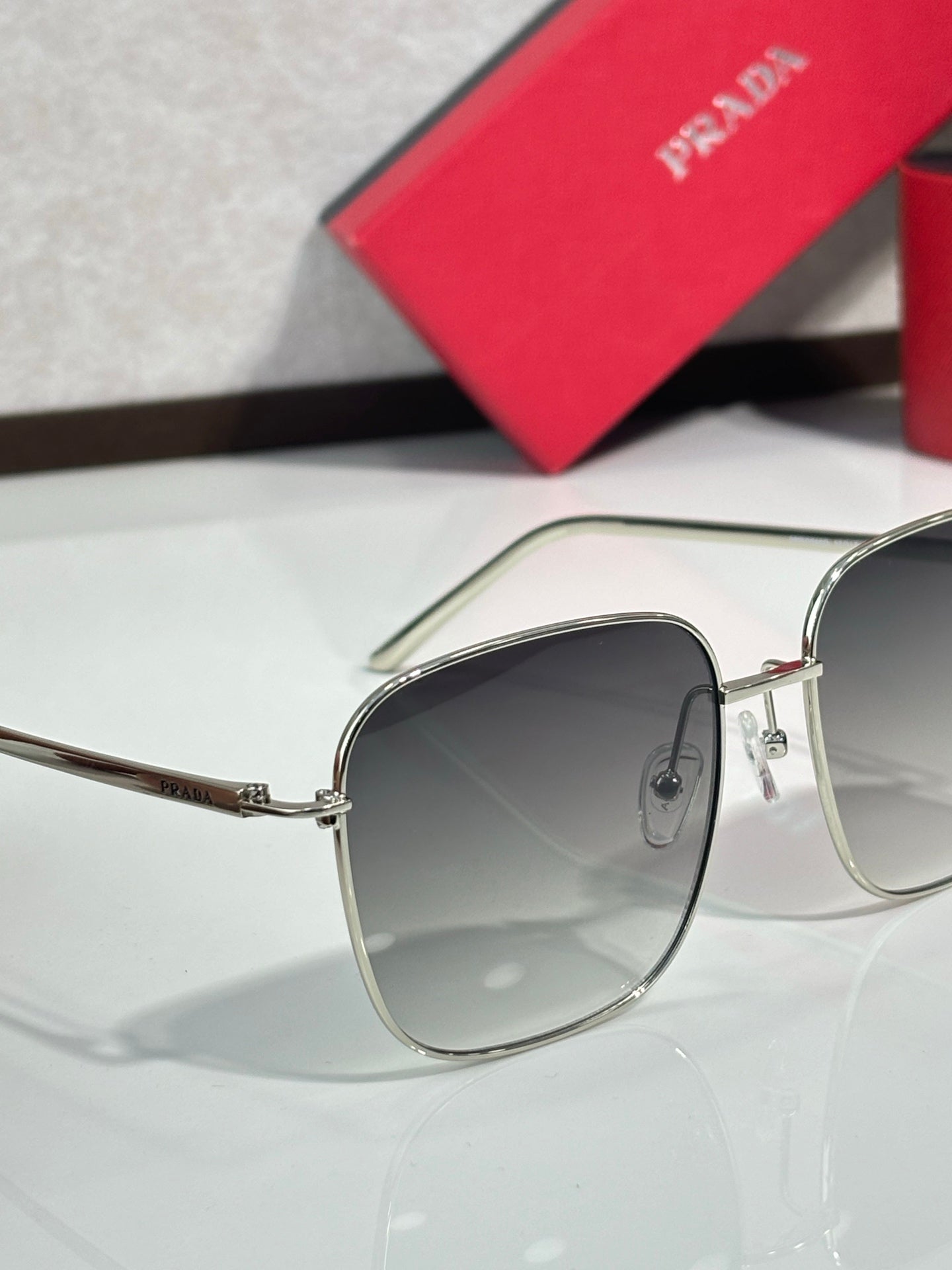 Prada sunglasses close-up with silver frame and dark gradient lenses, lens and frame detail